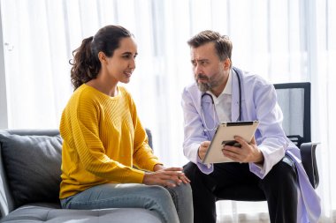 Erkek doktor ve kadın hasta konuşuyor ve hastanedeki hastaların hastalıkları hakkında tavsiyelerde bulunuyor.