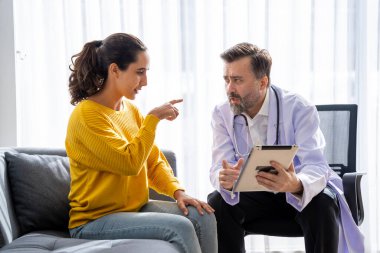 Erkek doktor ve kadın hasta konuşuyor ve hastanedeki hastaların hastalıkları hakkında tavsiyelerde bulunuyor.