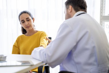 Erkek doktor ve kadın hasta konuşuyor ve hastanedeki hastaların hastalıkları hakkında tavsiyelerde bulunuyor.