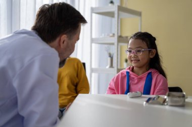 Erkek doktor ve kız hasta, hastanede hastalığınız hakkında konuşun ve tavsiyelerde bulunun..