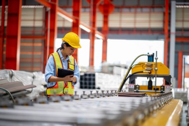 Metal levha fabrikasında çalışan genç bayan mühendis gerçek şantiyede denetleniyor. Profesyonel ve mutlu çalışın.
