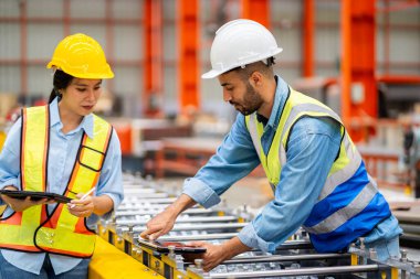 Metal levha fabrikasında çalışan genç erkek ve kadın mühendislerden oluşan bir ekip gerçek şantiyede denetleniyor. Profesyonel ve mutlu çalışın.