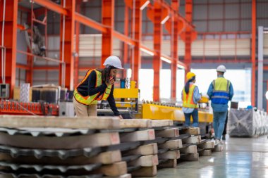 Metal levha fabrikasında çalışan genç bayan mühendis gerçek şantiyede denetleniyor. Profesyonel ve mutlu çalışın.