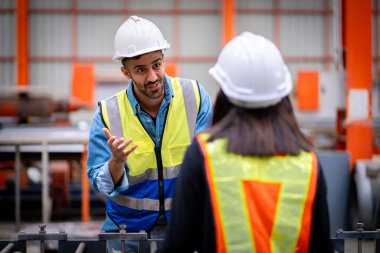 Metal levha fabrikasında çalışan genç erkek mühendis gerçek şantiyede denetleniyor. Profesyonel ve mutlu çalışın.