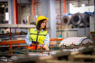 Metal levha fabrikasında çalışan genç bayan mühendis gerçek şantiyede denetleniyor. Profesyonel ve mutlu çalışın.