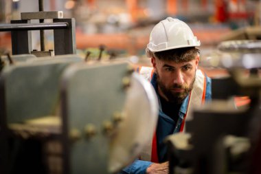 Metal levha fabrikasında çalışan genç erkek mühendis gerçek şantiyede denetleniyor. Profesyonel ve mutlu çalışın.