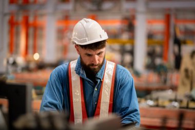 Metal levha fabrikasında çalışan genç erkek mühendis gerçek şantiyede denetleniyor. Profesyonel ve mutlu çalışın.