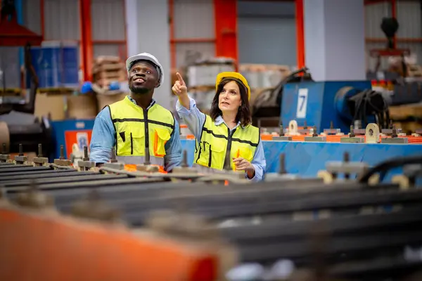 金属板工場で若い男性と女性エンジニアのチームが実際の現場で検査を受けています プロフェッショナルで幸せに仕事をする — ストック写真