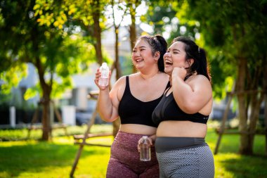 Sağlığını korumak için egzersiz yapan ve çimlerde eğlenceli bir şekilde kilo veren obez kadınlar..