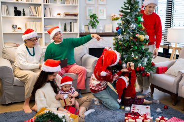 Noel günü Asyalı bir aile. Hediye ve turuncu ışıklarla dolu Noel temalı bir odada herkes mutlu..