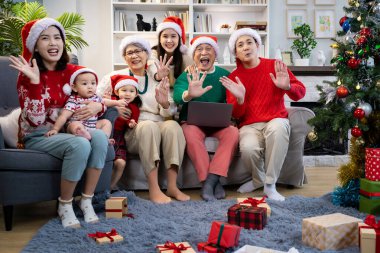 Noel günü Asyalı bir aile. Hediye ve turuncu ışıklarla dolu Noel temalı bir odada herkes mutlu..