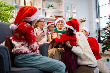 Noel günü Asyalı bir aile. Hediye ve turuncu ışıklarla dolu Noel temalı bir odada herkes mutlu..