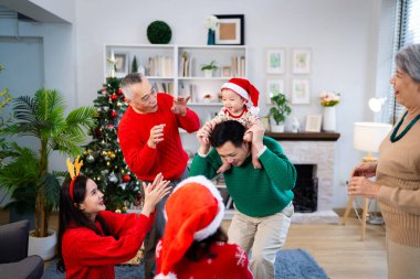 Noel günü Asyalı bir aile. Hediye ve turuncu ışıklarla dolu Noel temalı bir odada herkes mutlu..