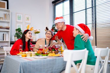 Noel günü Asyalı bir aile. Hediye ve turuncu ışıklarla dolu Noel temalı bir odada herkes mutlu..