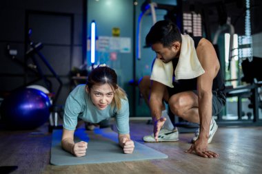 Asyalı erkek ve kadın spor yapıyor, biri antrenör, diğeri antrenör..