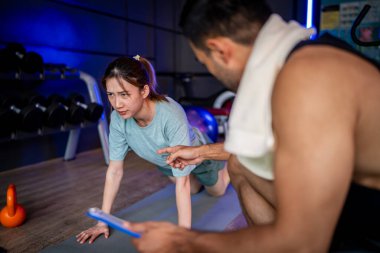 Asyalı erkek ve kadın spor yapıyor, biri antrenör, diğeri antrenör..