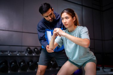 Asyalı erkek ve kadın spor yapıyor, biri antrenör, diğeri antrenör.