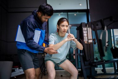 Asyalı erkek ve kadın spor yapıyor, biri antrenör, diğeri antrenör.