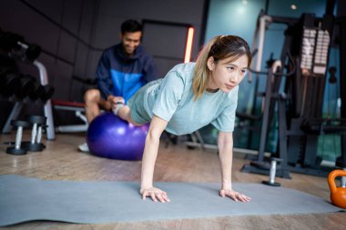 Asyalı erkek ve kadın spor yapıyor, biri antrenör, diğeri antrenör.