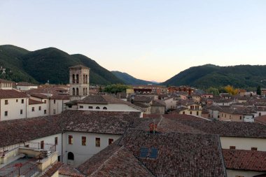 Rieti 'nin çatıları, yuvarlanan tepelerin arka planına karşı çarpıcı bir manzara yaratıyor. Günbatımının ılık renkleri bu İtalyan kasabasının cazibesini vurgulayarak tarihi mimariyi aydınlatıyor..