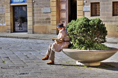 Siyah bir kadın kıvrımlı bir bankta oturur, bir kitaba dalmış, güneşle çevrili, ılık bir parıltı yayar, huzurlu bir atmosfer yaratır..