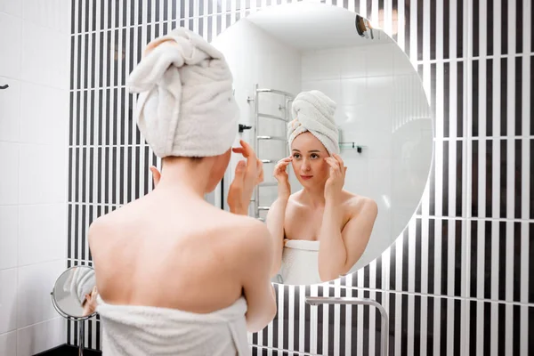 ホームバスルームで鏡の後ろに立つ抗しわクリームを適用する若い女性 美容と美容の手順 クレンジング後のスキンケア — ストック写真