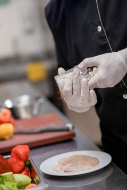 Close up of professional chef preparing chicken meat on restaurant kitchen. Culinary concept