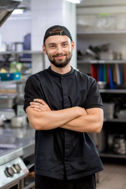 Portrait of professional smiling restaurant chef standing on kitchen background