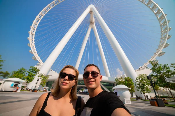Happy family tourists couple visits Ain (Eye) DUBAI - One of the largest Ferris Wheels in the World, located on Bluewaters island. Top tourists attractions in the United Arab Emirates