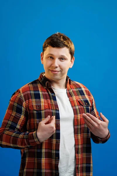 Happy handsome man pointing at himself, smiling pleased, Its me, promoting personal abilities, choose me gesture, standing over blue background and bragging