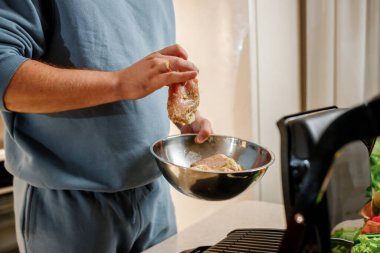 Adamın elleri ahşap masadaki elektrikli ızgarada lezzetli etli biftek hazırlıyor. Ev mutfağında sigara iç.