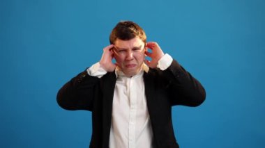 Handsome businessman looking at camera covering ears with hands say blah blah do not wanna listening over blue studio background