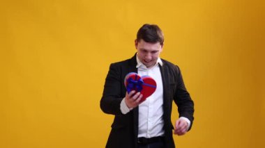 Happy businessman hugs receiving gift box to St.Valentine's Day on studio background. International Women's Day and birthday holiday concept