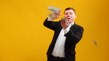 Businessman throws money, a wad of dollars in bills, towards the camera, very happily. Scatter the cash and funny dancing. Money rain, and falling. Concept of earned money, good business