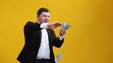 Businessman throws money, a wad of dollars in bills, towards the camera, very happily. Scatter the cash and funny dancing. Money rain, and falling. Concept of earned money, good business