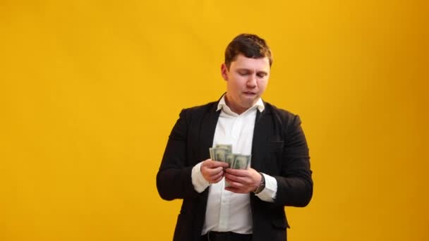 満足したビジネスマンはお金を数える 若い幸せな男黄色のスタジオの背景に現金ドルを計算します 財政と豊かさの概念 — ストック動画