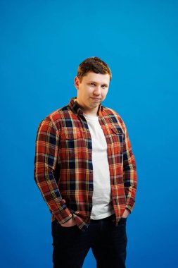 Portrait of handsome european man in shirt looking at camera standing on blue studio background