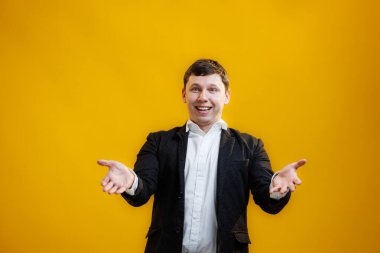 Handsome businessman standing with wide raised arms and welcoming or sharing, wearing official style suit on blue studio background. Wide open hug. Nice to meet you