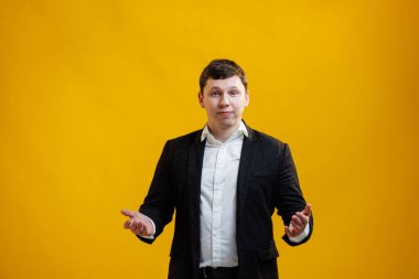 Handsome businessman standing with wide raised arms and welcoming or sharing, wearing official style suit on blue studio background. Wide open hug. Nice to meet you