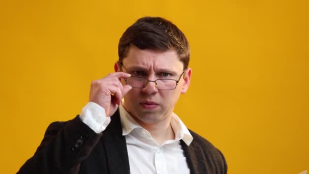 Serious Businessman Putting Glasses Showing You Yellow Studio Background — Video