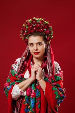 Portrait of ukrainian woman in traditional ethnic clothing and floral red wreath on viva magenta studio background. Ukrainian national embroidered dress call vyshyvanka. Pray for Ukraine