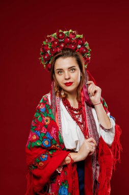 Portrait of ukrainian woman in traditional ethnic clothing and floral red wreath on viva magenta studio background. Ukrainian national embroidered dress call vyshyvanka. Pray for Ukraine