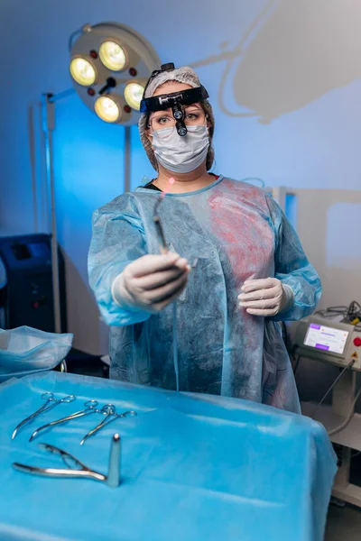 Portrait of professional female surgeon proctologist before operation holding an anoscope in the operating room in hospital. Urgent surgical concept
