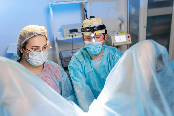 Profesyonel cerrah proktolog ekibi hastanedeki ameliyathanede özel tıbbi cihazlar kullanarak ameliyat yapıyor. Acil cerrahi konsept