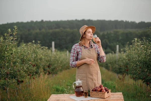 Szczęśliwa Uśmiechnięta Pracownica Rolnicza Pijąca Smaczny Sok Jabłkowy Szkle Stojąca — Zdjęcie stockowe