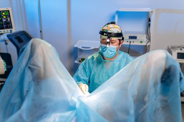 Profesyonel erkek cerrah proktolojist hastanedeki ameliyathanede özel tıbbi aletler kullanarak ameliyat yapıyor. Acil cerrahi konsept