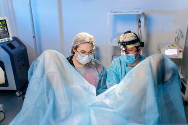 Profesyonel cerrah proktolog ekibi hastanedeki ameliyathanede özel tıbbi cihazlar kullanarak ameliyat yapıyor. Acil cerrahi konsept