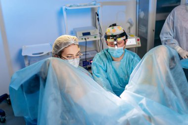 Profesyonel cerrah proktolog ekibi hastanedeki ameliyathanede özel tıbbi cihazlar kullanarak ameliyat yapıyor. Acil cerrahi konsept