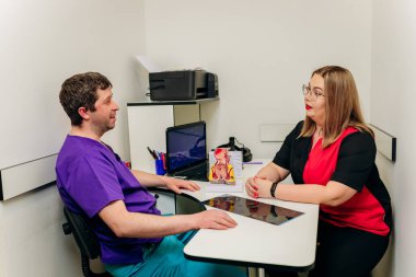 İki doktor proktolog insan rektumunun yapay modeline bakıp, klinikte hastanın hastalıklarını ya da teşhisini tartışıyor.