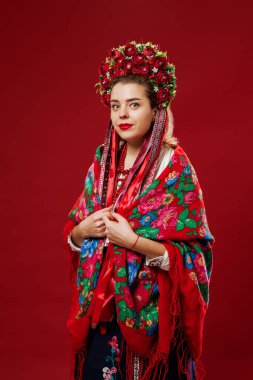 Portrait of ukrainian woman in traditional ethnic clothing and floral red wreath on viva magenta studio background. Ukrainian national embroidered dress call vyshyvanka. Pray for Ukraine